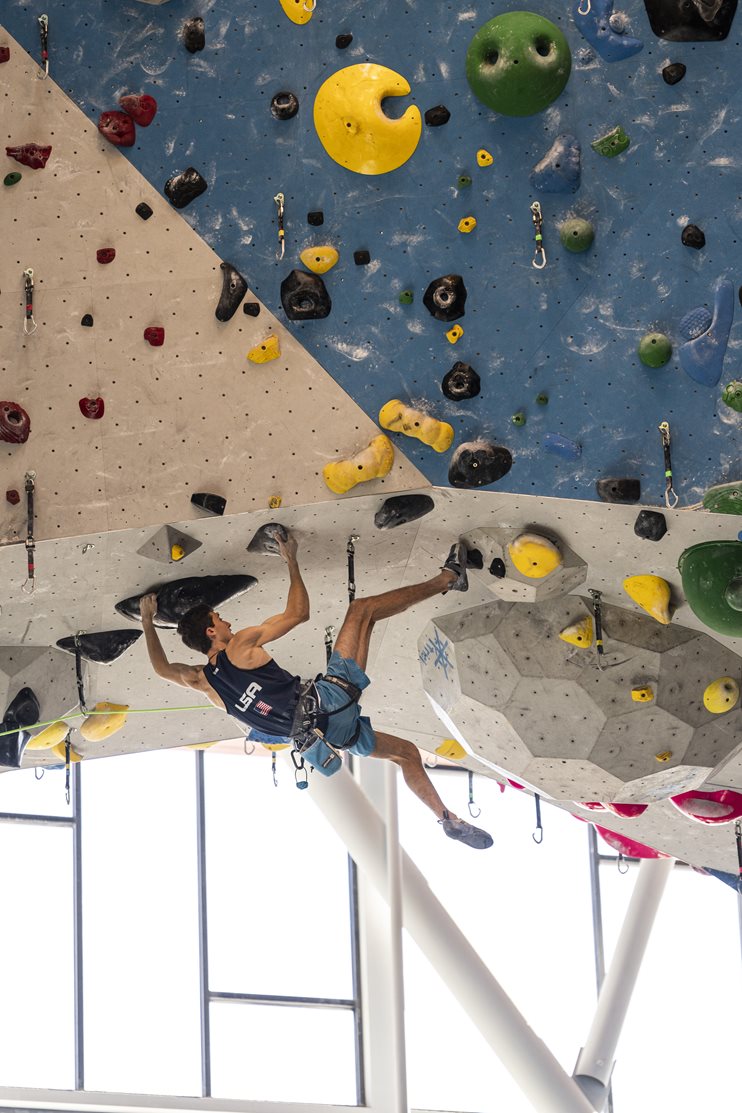 Jesse in silhouette climbing on an overhang in the climbing gym © Gabe Mayberry @mayberrygabriel